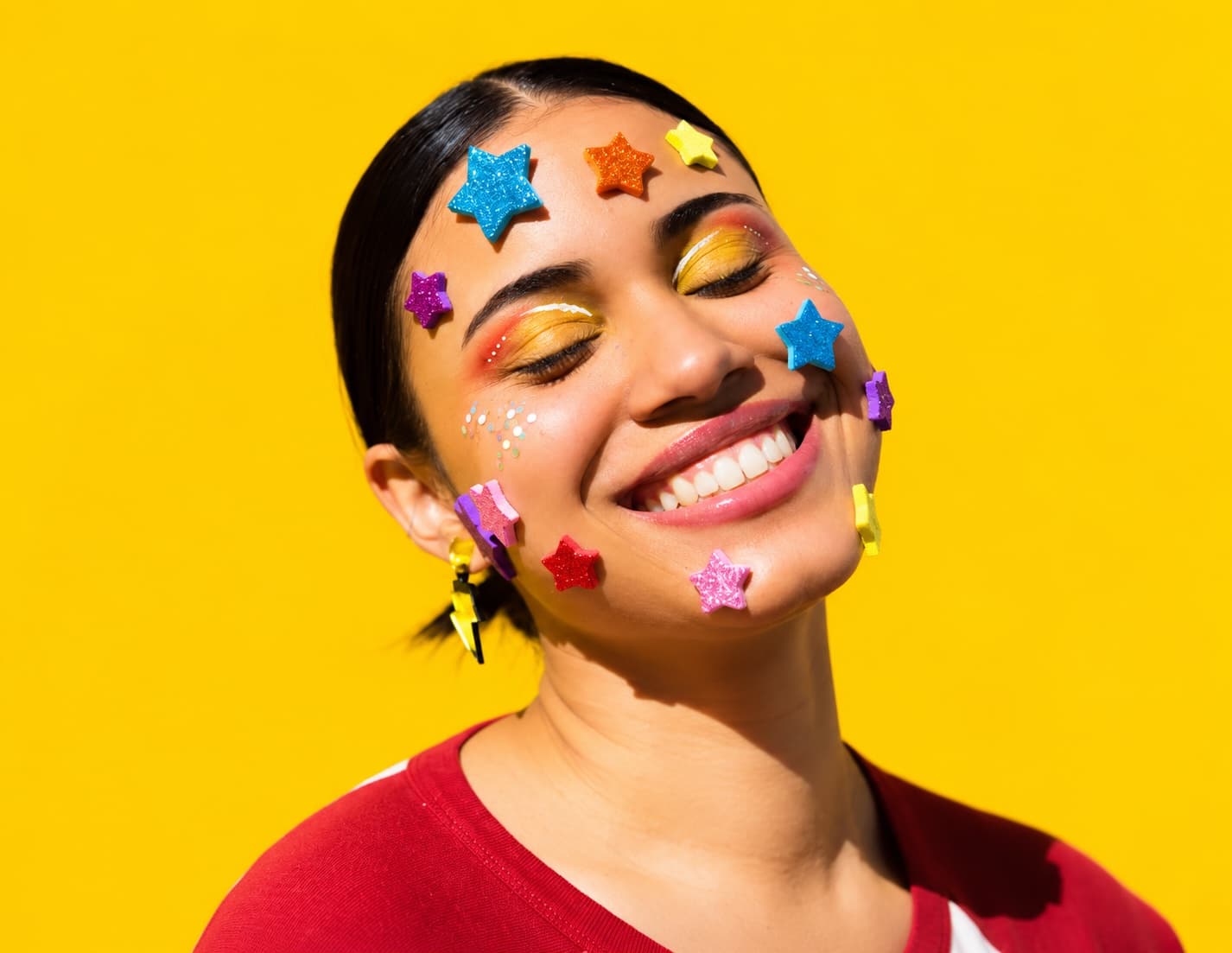 Woman smiling with colorful star stickers on a yellow background